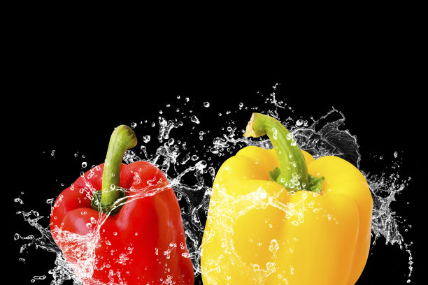鲜辣椒红、黄与水飞溅孤立在黑色背景上图片下载