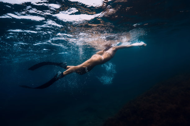 游泳运动女人与鳍在蓝色的海洋。图片下载