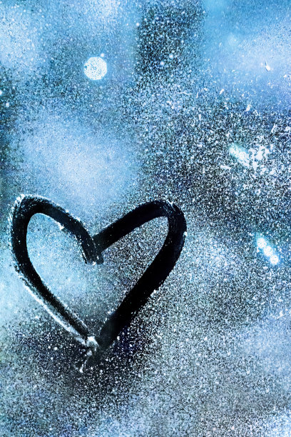 在冰冻的玻璃上画着一颗蓝色背景的心图片下载