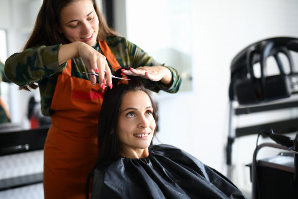 愉快的女理发师穿着围裙，用剪刀给客人剪了头发。图片下载