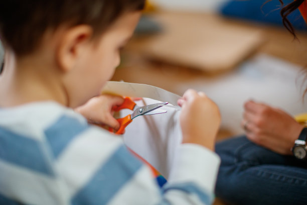 蹒跚学步的孩子用剪刀剪纸图片下载