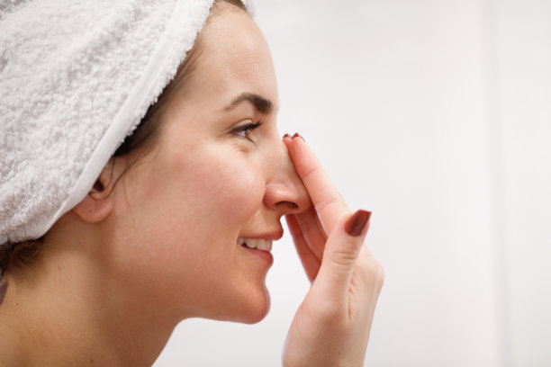 侧面的女人在她的鼻子上涂面霜图片下载