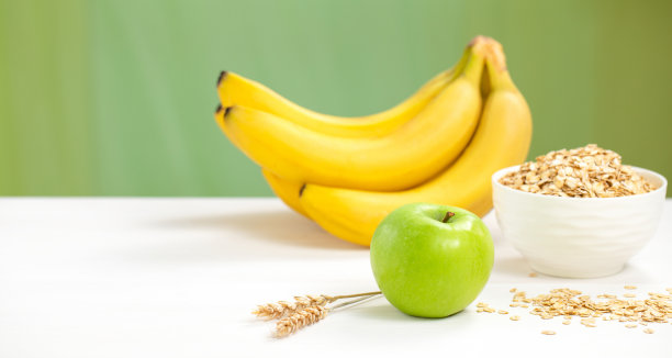 健康早餐配料燕麦和水果:香蕉，苹果。白色和绿色背景上的有机食品。侧视图，拷贝空间。图片下载