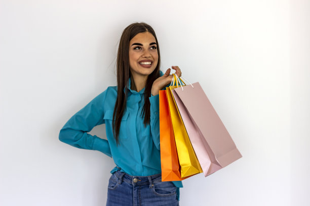 一个兴奋的年轻女子举着她五颜六色的购物袋。图片下载