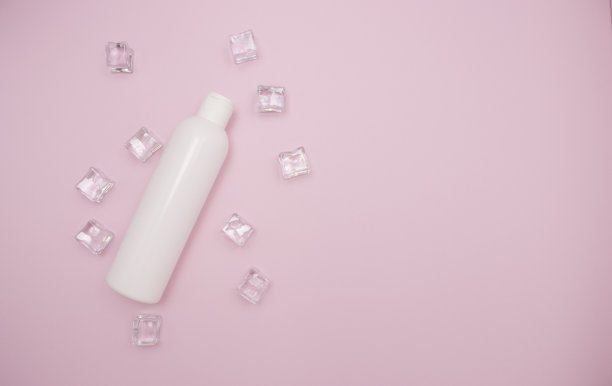 白色塑料瓶洗发水或其他化妆品。冰块周围，粉色背景，自由的文字空间，俯视图。图片下载
