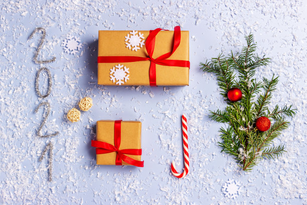 用牛皮纸包装的礼盒，红丝带，有球的圣诞树枝，2021年，糖果棒在灯光背景。前视图。礼物送给节日，圣诞节图片下载