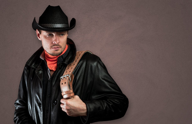 穿着皮衣，手里拿着皮带的牛仔。图片下载