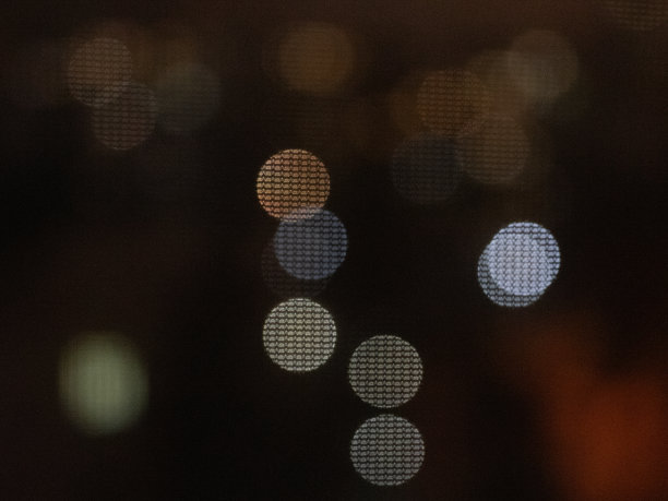 窗帘后面窗户上的圣诞花环。照亮城市景观的模糊和散焦效果图片下载