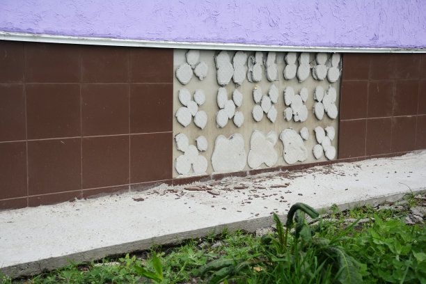 在外面的混凝土基础上铺设瓦片是一种糟糕的变化，因为房屋建筑外墙的瓦片由于水的破坏而从墙上脱落。糟糕的瓷砖工作的例子。图片下载