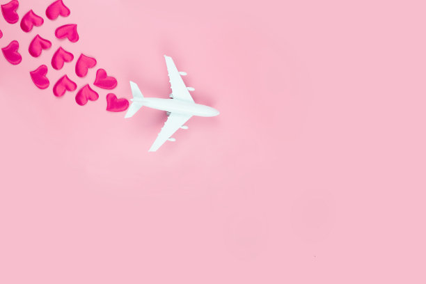 情人节快乐。玩具飞机和红色的心，在粉红色的背景图片下载