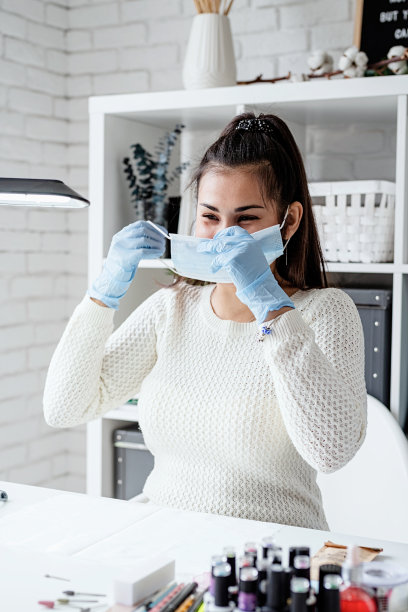 美甲大师戴着橡胶手套戴着面具在美容工作室室内图片下载