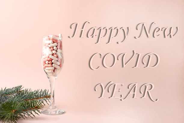 概念，2019冠状病毒病的新年。萨满玻璃杯里装满了白色和粉色的药丸。粉红色背景上的题词。图片下载