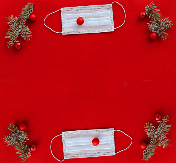 电晕和圣诞节。一个防护面具旁边的圣诞树球和冷杉树枝在红色的背景图片下载