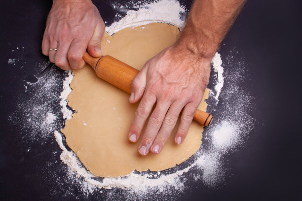 男人的手在黑色的桌子上擀面团。从以上观点。圣诞节的概念图片下载