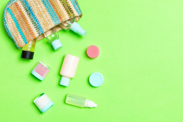 女人化妆包与一套美容产品和身体护理霜在绿色的背景与复制空间为您设计图片下载