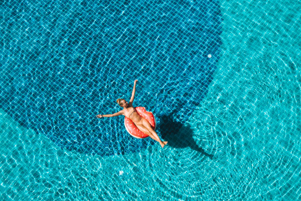 在游泳池里，一个女人漂浮在充气筏上图片下载