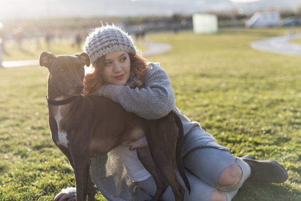 日落时分，公园里的一名女子和她的猎犬互相拥抱图片下载