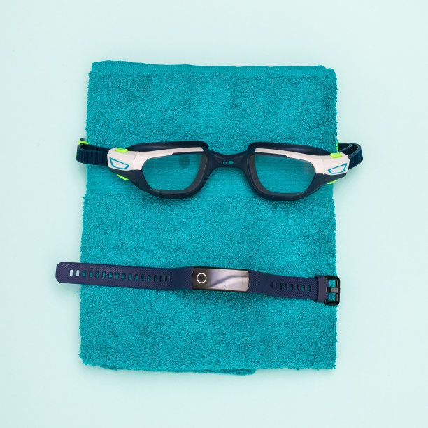 游泳护目镜，智能手镯和毛巾在蓝色背景。图片下载