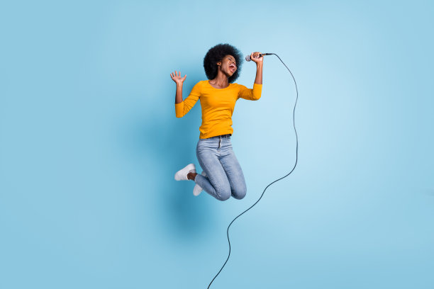 照片肖像完整长度的唱歌女人拿着麦克风在一只手跳起来孤立的淡蓝色背景图片下载