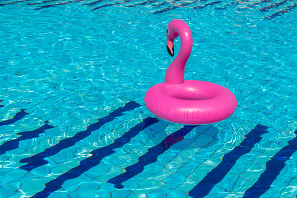 夏天出售。粉红色的充气火烈鸟在游泳池的水为夏天的海滩背景。最小的夏天的概念。图片下载