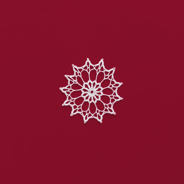 红色背景上孤立的雪花。手工装饰编织的雪花垫。冬天或圣诞节的装饰。广场的大小图片下载