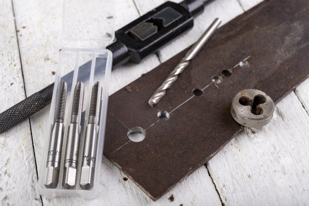 用来切割金属螺纹的丝锥和板牙。锁匠车间的配件。光背景。图片下载