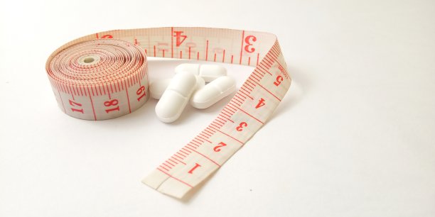 概念特写，药物控制的插图保持健康但理性，塑料粉色裁缝仪和白色药丸图片下载