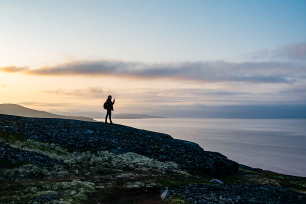 年轻女子旅行者的剪影享受北欧自然的美丽在山附近的海边拍摄日落的照片图片下载