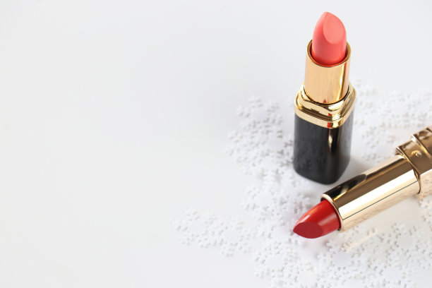 两支红色唇膏和白色背景上的装饰性雪花。孤立。副本的空间。化妆品的概念。图片下载