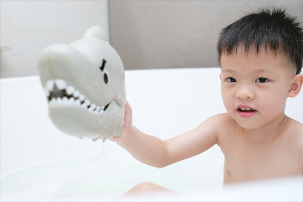 可爱的亚洲微笑幼儿园男孩孩子有乐趣在浴缸浴室，快乐的孩子享受洗澡时间，孩子被留在独自洗澡图片下载