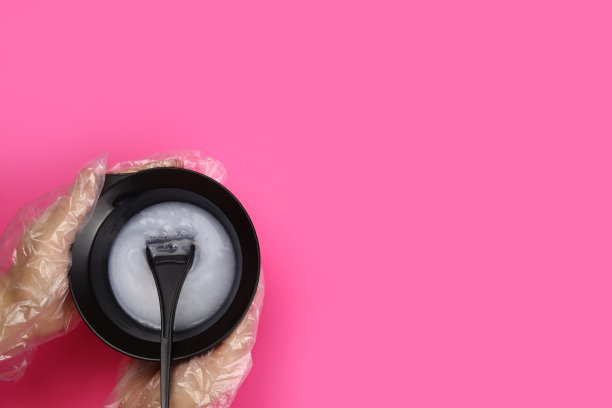 发型师手持染发剂，用刷子将染发剂放入混色碗中图片下载