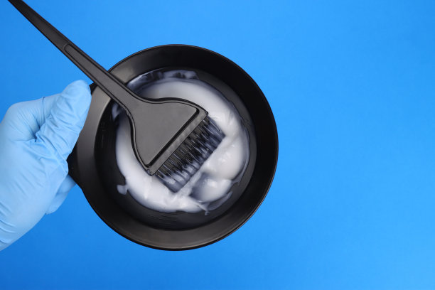 发型师手持染发剂，用刷子将染发剂放入混色碗中图片下载