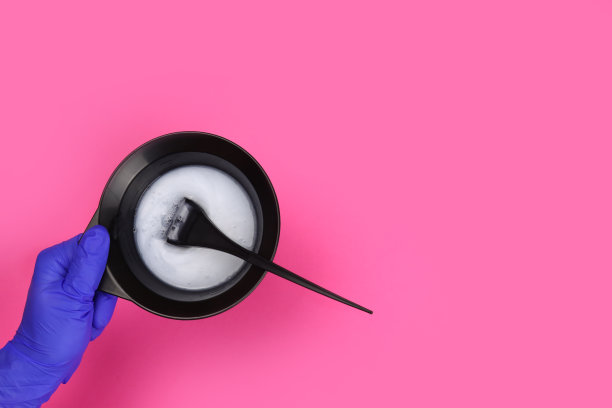 发型师手持染发剂，用刷子将染发剂放入混色碗中图片下载