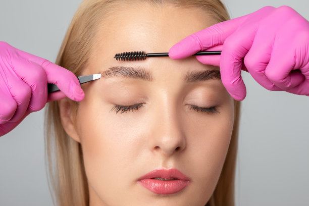 化妆师在美容院染发后梳眉毛、拔眉毛。专业的化妆美容护肤。图片下载