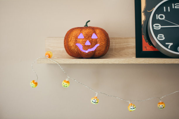 万圣节南瓜在书架上闪闪发光-假日，装饰和派对概念-家庭背景图片下载