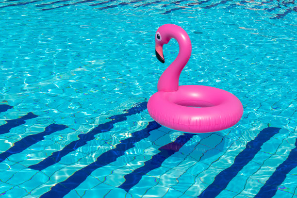 海的背景。粉红色的充气火烈鸟在游泳池的水为夏天的海滩背景。奢侈的生活方式。图片下载