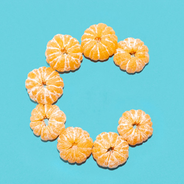 蓝色背景下剥了皮的橘子中字母C的创意布局。Flatlay。图片下载