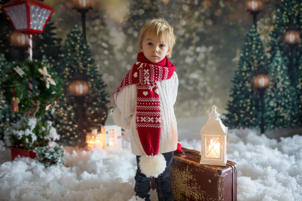 一个蹒跚学步的孩子拿着手提箱和小姜黄色人玩具，走在白雪覆盖的森林里，圣诞照片图片下载