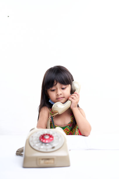 年轻的亚洲学步儿童在老式电话与可爱的表情图片下载