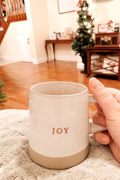 2020年一个温馨的圣诞节，一个女人蜷缩在杯子里，喝着热可可，在寒冷的夜晚说着“快乐”图片下载