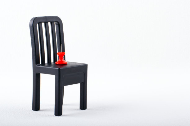 黑色小椅子上的红色图钉。工作中的风险概念。图片下载