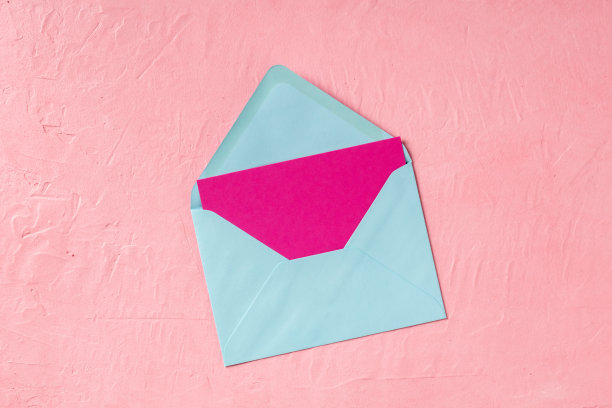 粉红色贺卡或邀请模型在一个蓝色信封，从上方与copyspace拍摄图片下载