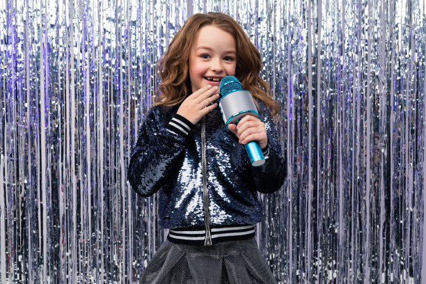 漂亮的年轻白人女孩拿着麦克风，背景是金箔图片下载