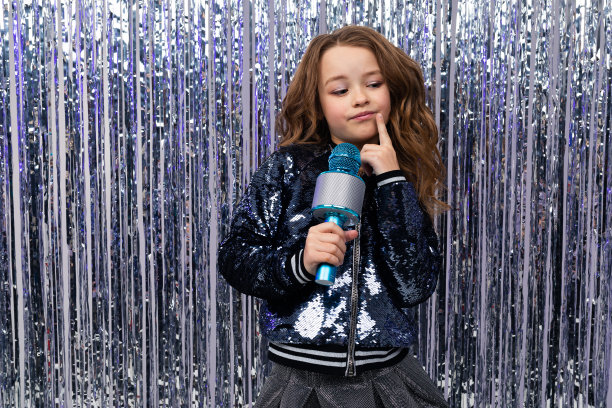 一个沉思的时尚女孩，手里拿着一个麦克风，背景是闪亮的金属箔图片下载