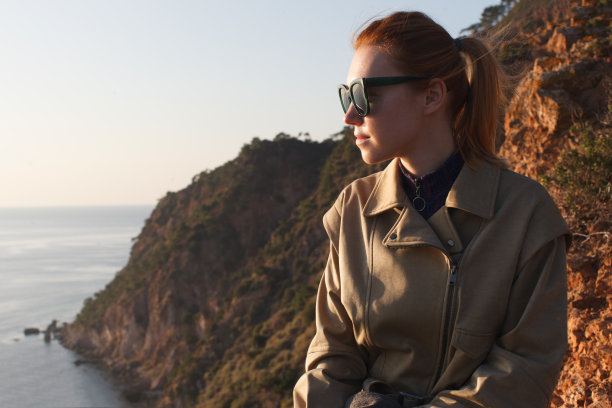 年轻可爱的旅行女人在岩石海岸图片下载