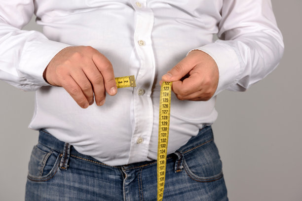 超重男子用卷尺量肚子图片下载