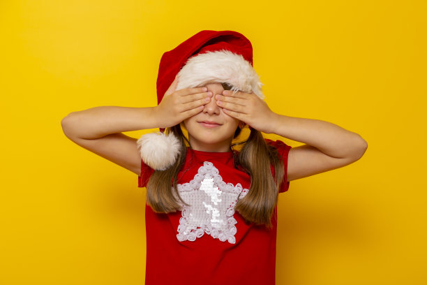 小女孩戴着圣诞帽，双手捂住眼睛图片下载