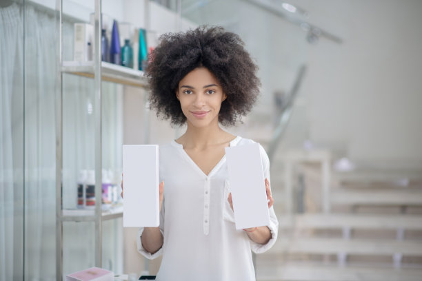 微笑的女人站在室内展示化妆品的包装图片下载