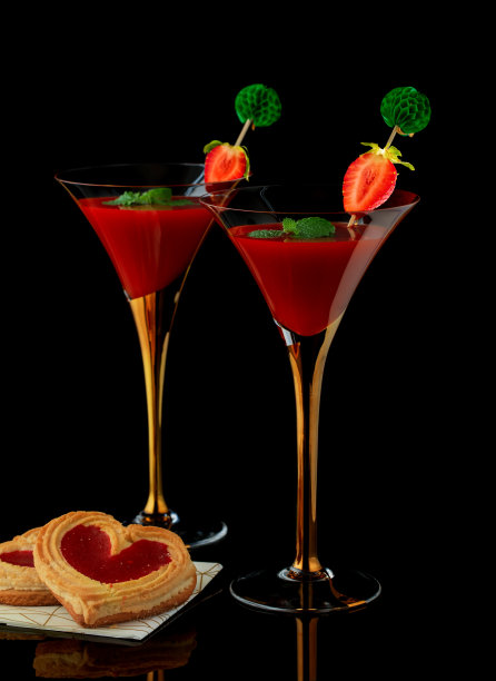 两杯草莓汁，玛格丽塔或红色马提尼鸡尾酒和心型饼干孤立在黑色背景反射。情人节贺卡。图片下载
