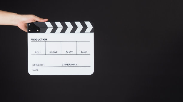 手在黑色背景上握住白色拍板或电影板。图片下载